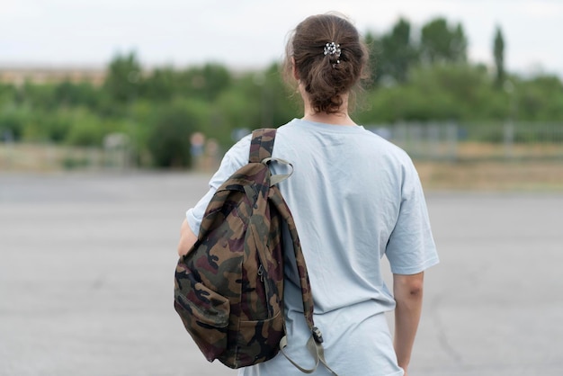 Un joven con el pelo largo parado al aire libre con una mochila