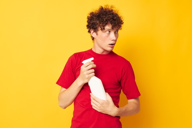 Joven de pelo rizado con detergentes de camiseta roja en las manos posando Estilo de vida inalterado