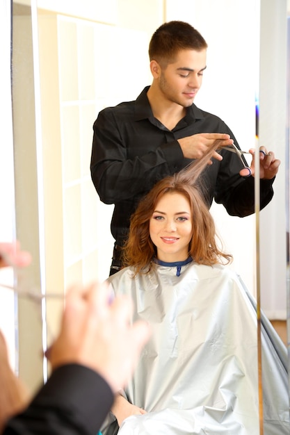Foto joven peluquero hacer peinado chica en salón de belleza