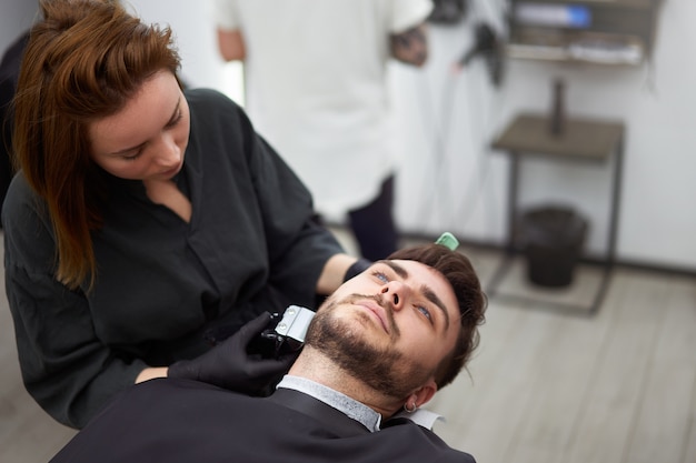 Joven peluquero peinando la barba de un cliente