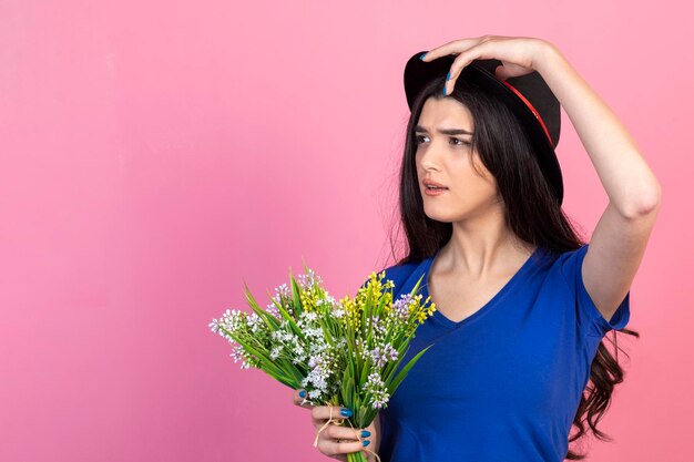 Una joven pensativa sosteniendo un ramo de flores y mirando a un lado