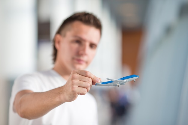 Joven con pequeño avión en el aeropuerto esperando su vuelo