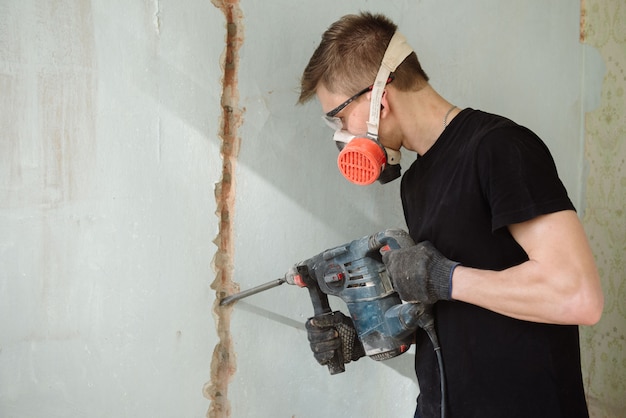 Un joven perfora una pared con un perforador.