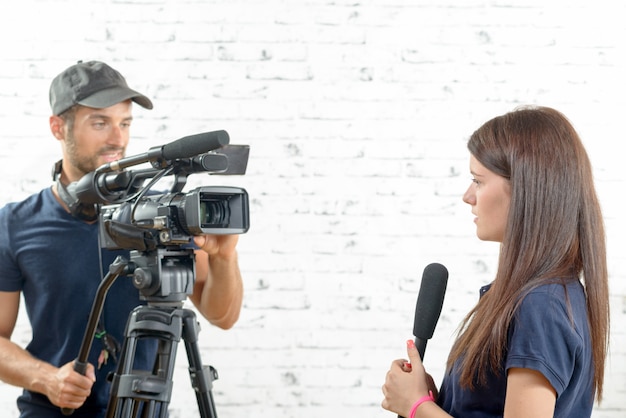 Joven periodista con micrófono y camarógrafo