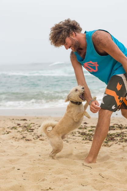 Joven con perro jugando en la playa