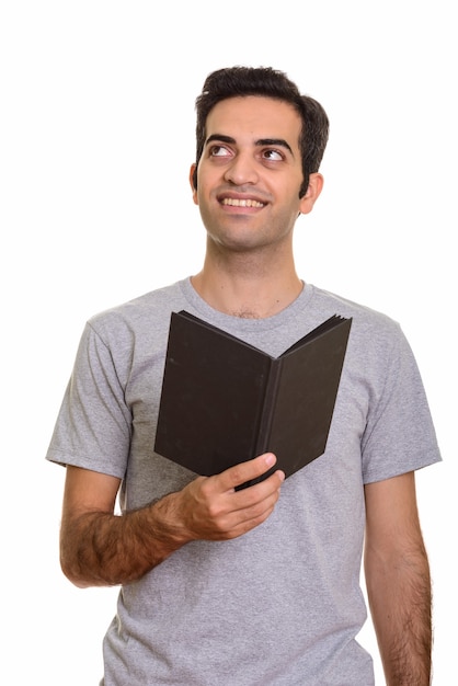 Joven persa feliz sosteniendo el libro mientras piensa aislado