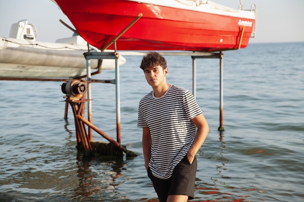 Joven pescador posando cerca de barcos de pescadores