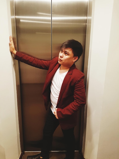 Foto joven de pie contra el ascensor