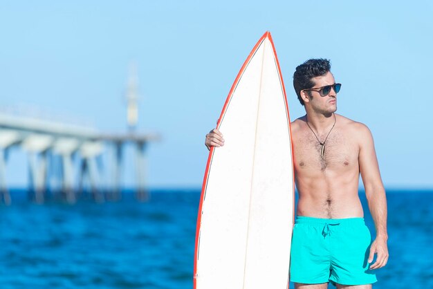 Joven de pie junto al mar contra el cielo