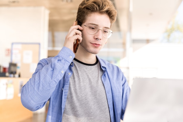 Joven con piercings hablando por un teléfono celular con una expresión seria