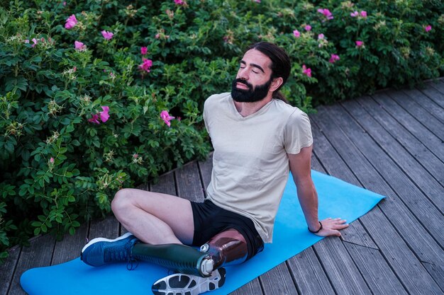 Joven con pierna ortopédica haciendo estiramientos después de una tarde de entrenamiento al aire libre