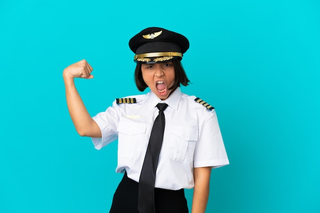 Joven piloto de avión sobre fondo azul aislado celebrando una victoria