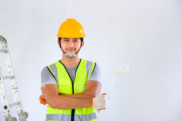 Joven pintor asiático Feliz pintando las paredes dentro de la casa blanca con un rodillo de pintura en una casa nueva. Idea de decoración del hogar