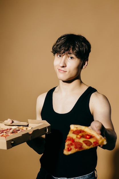 Joven con pizza sobre un fondo de color