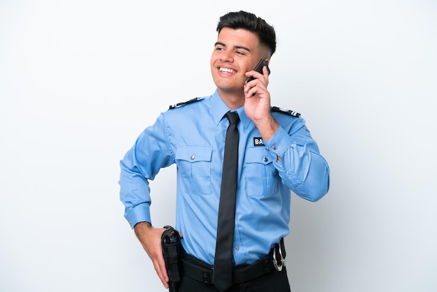 Joven policía caucásico aislado de fondo blanco manteniendo una conversación con el teléfono móvil