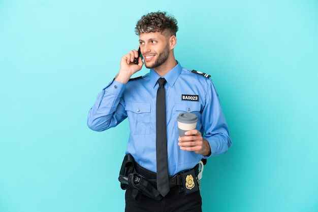 Joven policía rubio aislado blanco sobre fondo azul con café para llevar y un móvil