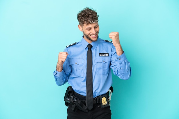 Joven policía rubio hombre aislado blanco sobre fondo azul celebrando una victoria