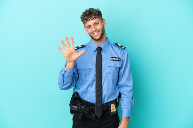 Joven policía rubio hombre aislado blanco sobre fondo azul contando cinco con los dedos