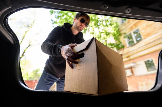 Foto joven pone una caja en el coche