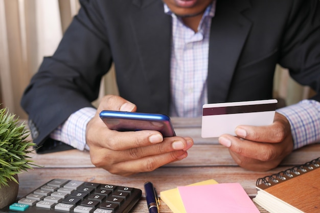 Foto joven poniendo detalles de la tarjeta de crédito en el teléfono inteligente.