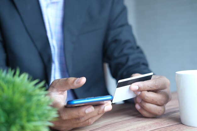 Foto joven poniendo detalles de la tarjeta de crédito en el teléfono inteligente.