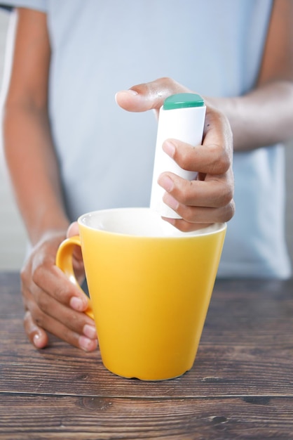 Joven poniendo edulcorante artificial en el té