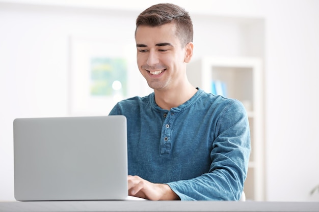 Joven con portátil moderno en la mesa