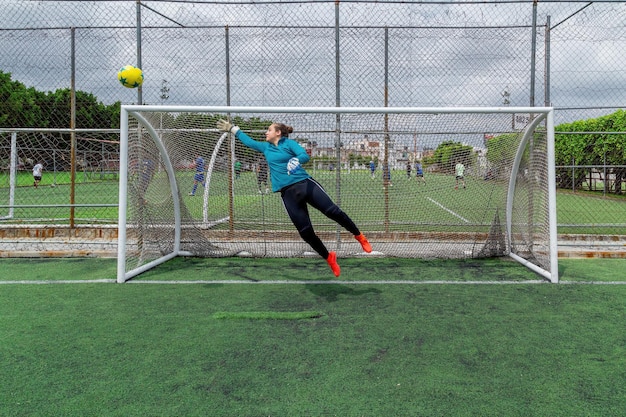 Joven portera hispana tratando de atrapar una pelota