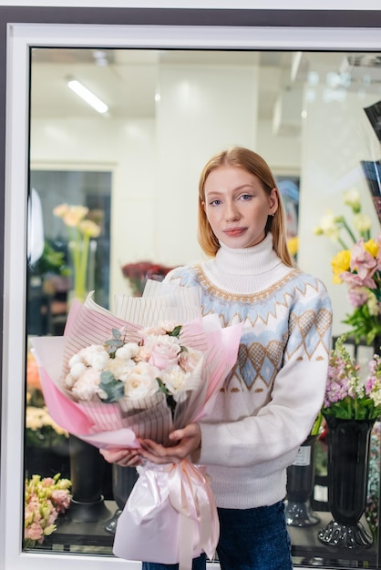 Foto una joven posa con un hermoso ramo festivo en el contexto de una acogedora florería floristería y elaboración de ramos en una floristería pequeña empresa