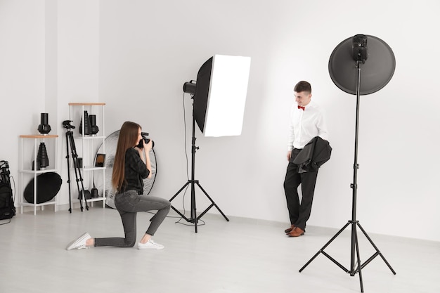 Foto joven posando para fotógrafo profesional sobre fondo blanco en estudio