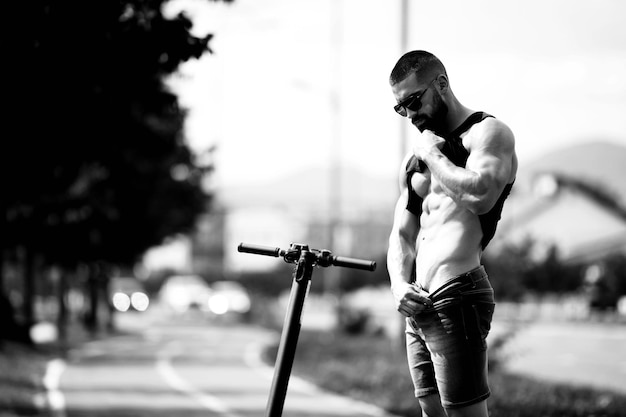 Joven posando junto a scooter eléctrico a lo largo de la calle en la ciudad