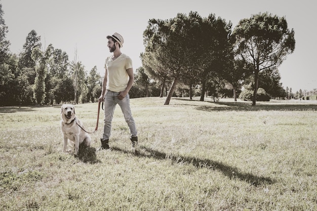 Joven posando con su perro labrador canadiense en un parque urbano