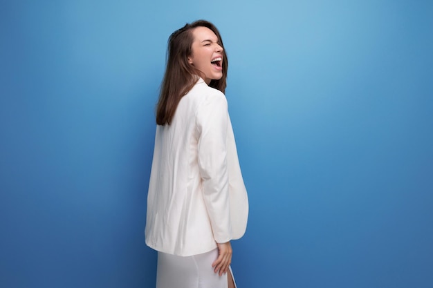 Joven positiva con cabello oscuro debajo de los hombros con un vestido blanco