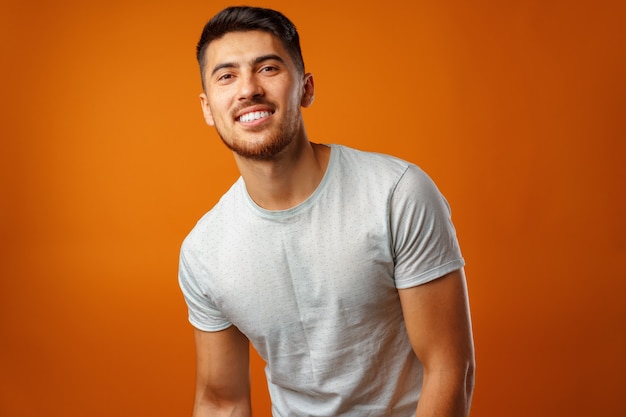 Foto joven positivo en camisa casual blanca de pie con sonrisa feliz de cerca