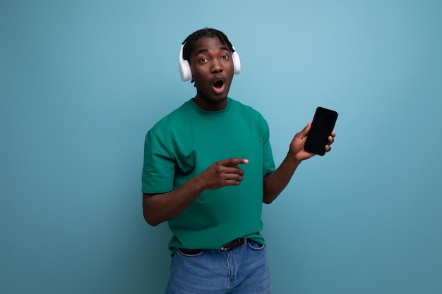 Joven positivo escuchando música con auriculares y teléfono inteligente