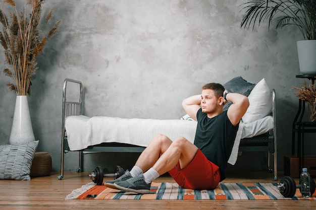 Joven practica deportes en casa, entrenando en línea. El deportista hace la prensa