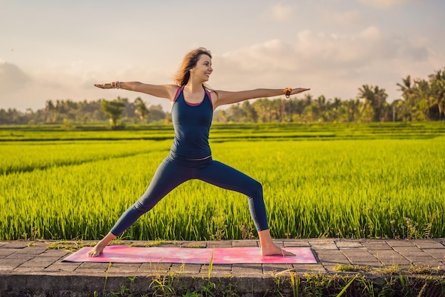 Una joven practica yoga al aire libre en campos de arroz por la mañana durante un retiro de bienestar en Bali