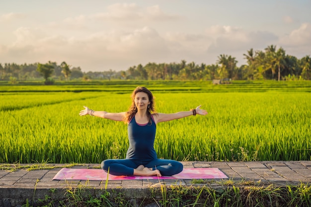 Una joven practica yoga al aire libre en campos de arroz por la mañana durante un retiro de bienestar en Bali