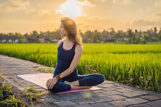 Una joven practica yoga al aire libre en campos de arroz por la mañana durante un retiro de bienestar en Bali