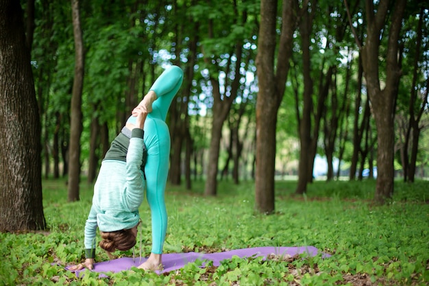 Joven practica yoga en un bosque verde