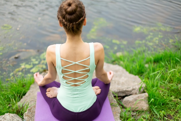 Joven practica yoga cerca de un río