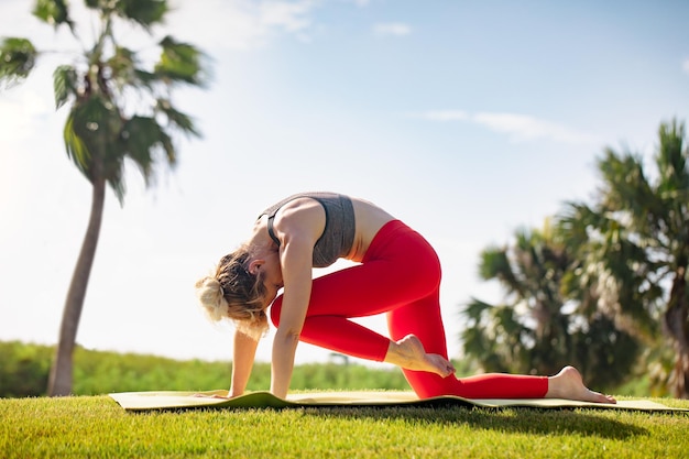 Una joven practica yoga en la costa del océano durante el amanecer.