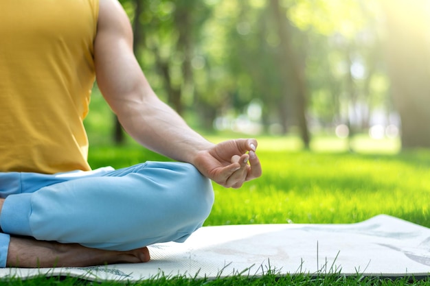 Joven practica yoga en el parque. Asanas de yoga en el parque de la ciudad, día soleado. Concepto de meditación, bienestar y estilo de vida saludable