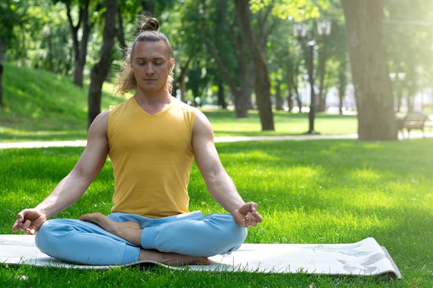 Joven practica yoga en el parque. Asanas de yoga en el parque de la ciudad, día soleado. Concepto de meditación, bienestar y estilo de vida saludable