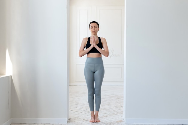 Una joven practica yoga, reza y comprende el zen en el arco de una habitación luminosa. El concepto de un estilo de vida saludable, meditación y tranquilidad.