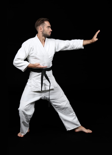 Joven practicando karate sobre fondo oscuro