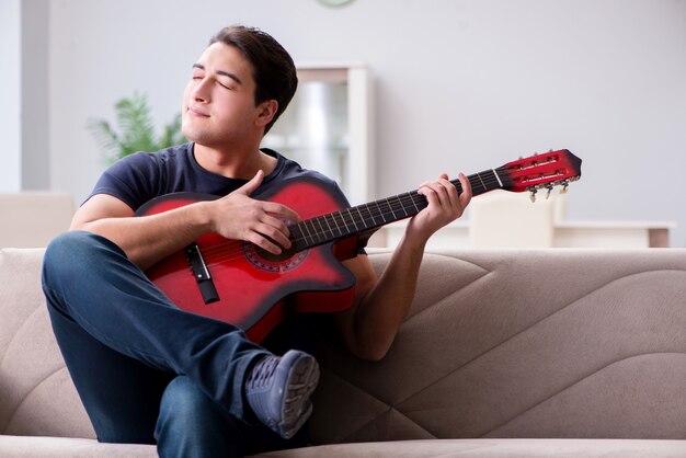 Joven practicando tocar la guitarra en casa