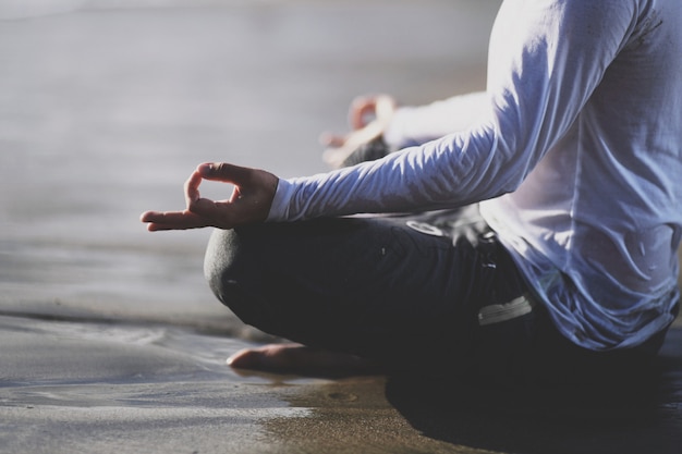 Joven practicar yoga en la playa al atardecer.