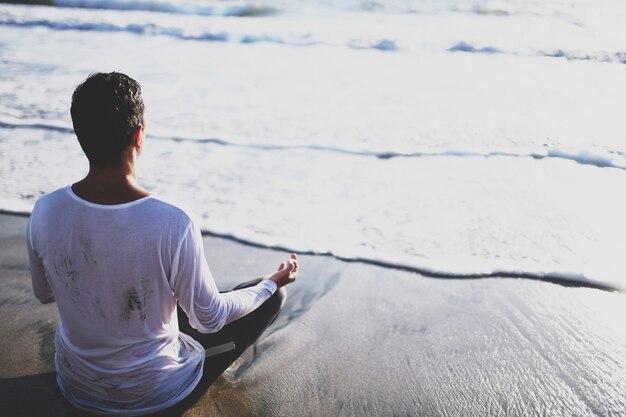 Joven practicar yoga en la playa al atardecer.