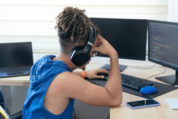 Joven preocupado trabajando en casa con su computadora y auriculares haciendo una videollamada